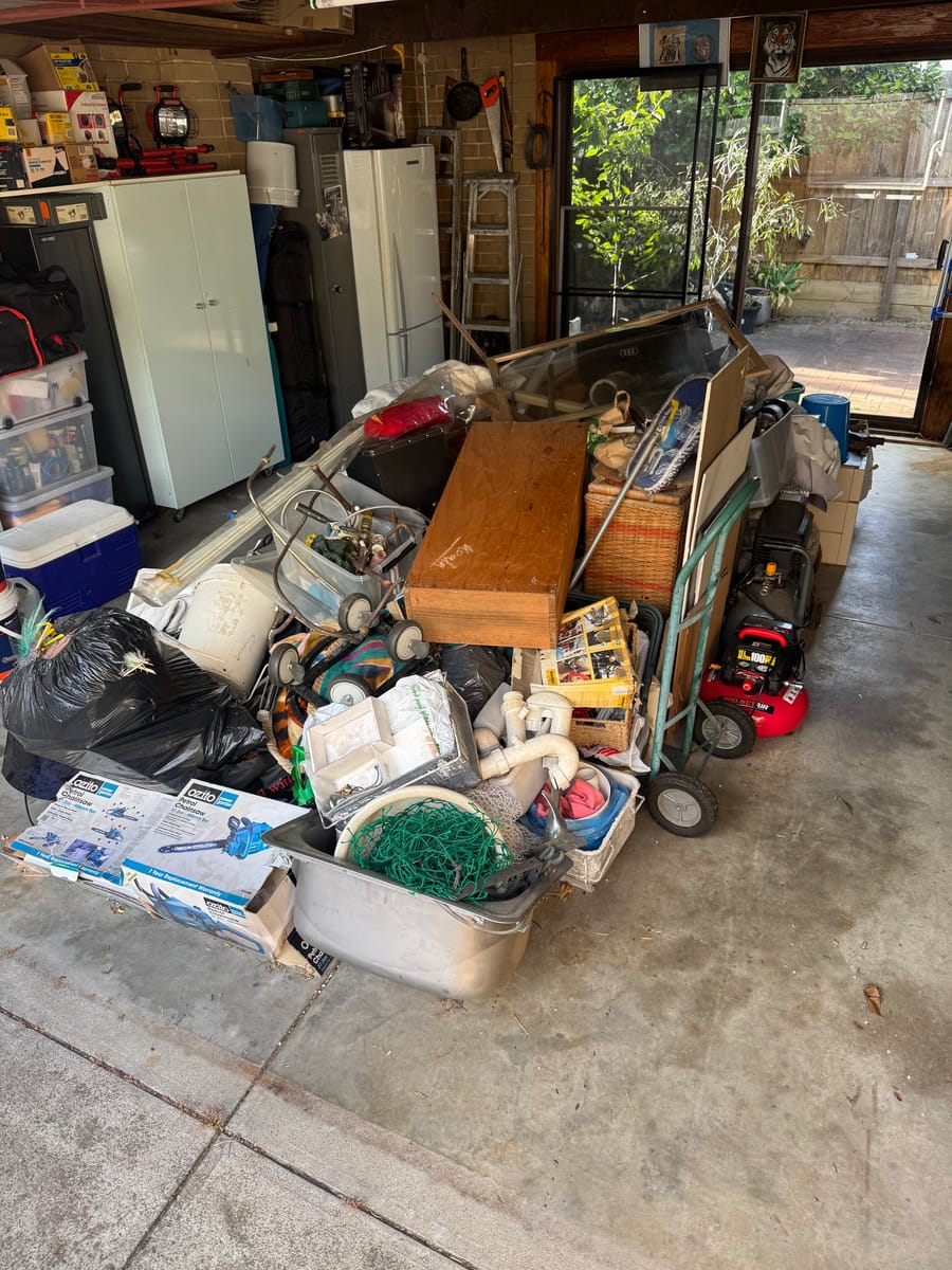 Carport piled with old furniture and junk before garage and carport cleanout in Melbourne