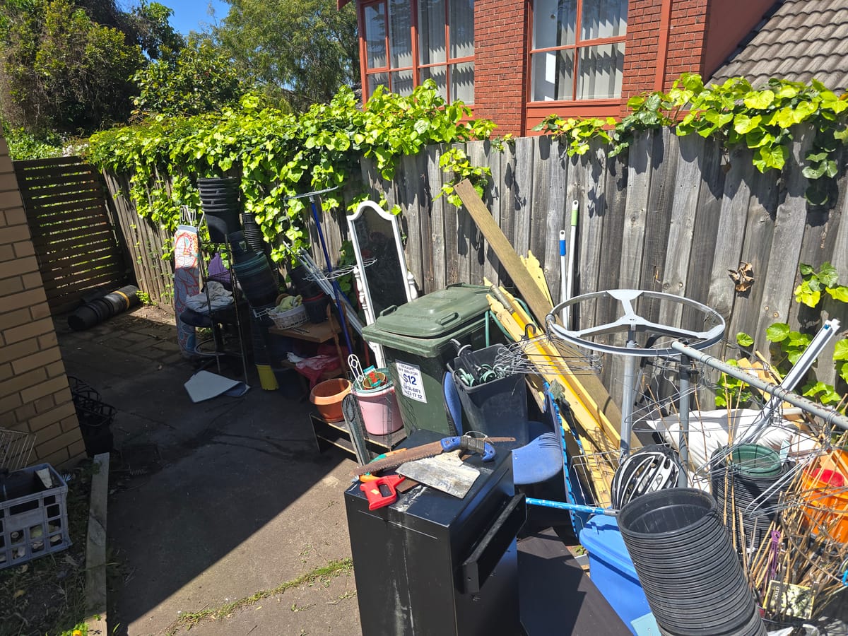 Side yard cluttered with bikes and junk before a real estate cleanout in Melbourne