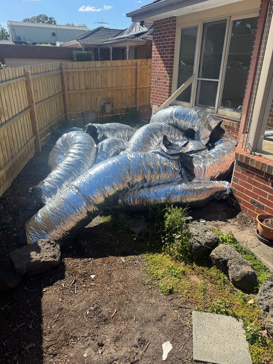 Backyard piled with a mattress and renovation junk before waste removal in Melbourne